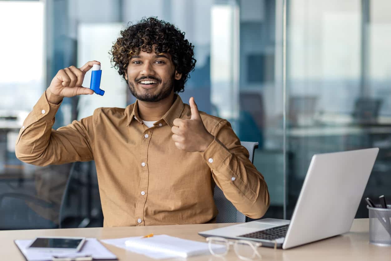 A student holding an inhaler happy he got relief from his asthma 