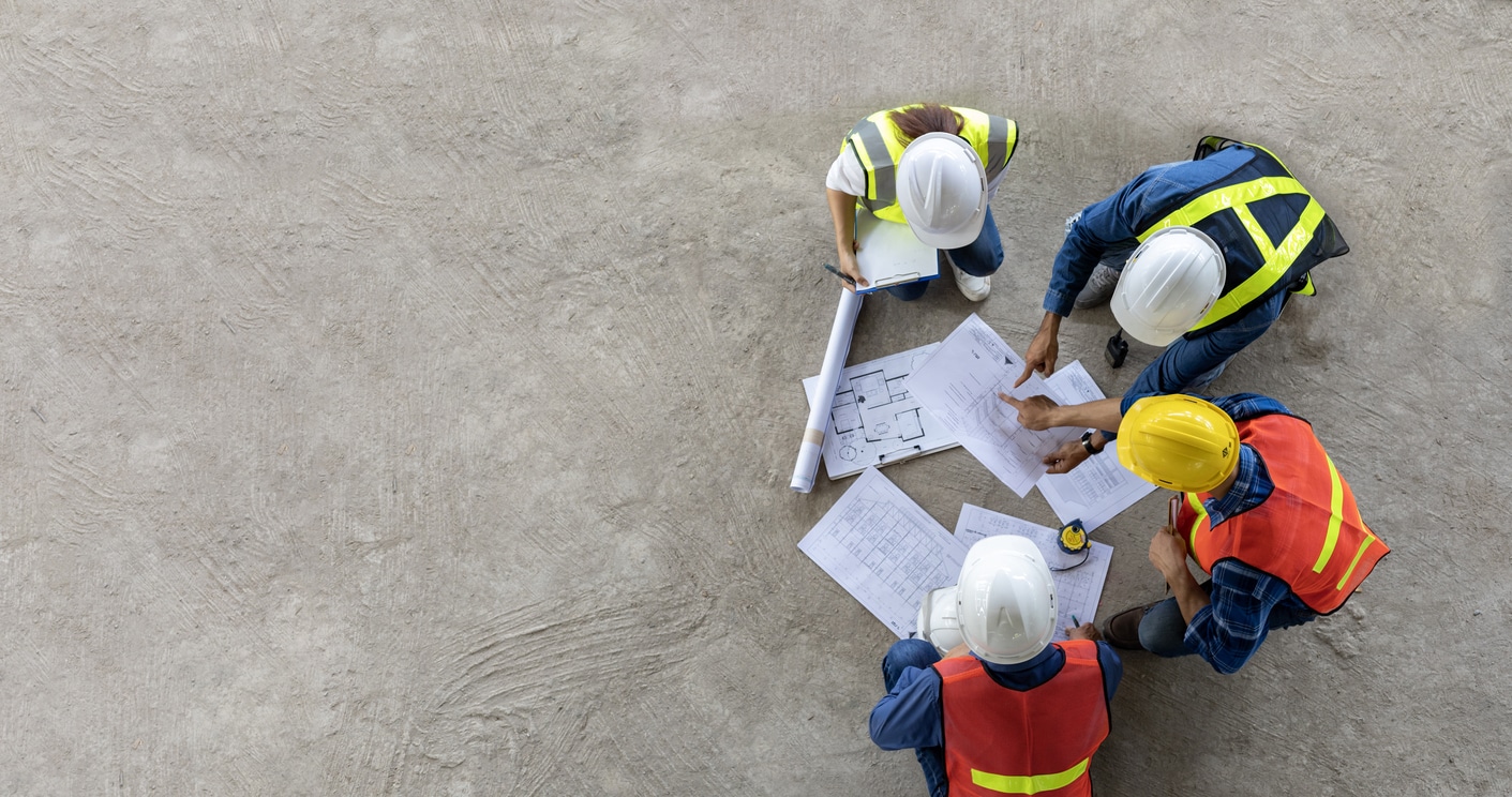 An up top view looking down on a team of supervisors meeting together over blueprints